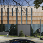Exterior view of The Burke Museum, featuring a modern architectural design with a distinctive facade that incorporates natural materials and large glass windows. The building is surrounded by landscaped areas, including native plants and pathways, creating an inviting atmosphere. The design reflects the museum's focus on natural history and cultural heritage, emphasizing its role as a center for education and community engagement.