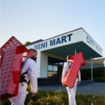 Exterior view of the Mini Mart project, showcasing a modern and inviting design with a prominent storefront featuring large glass windows and a colorful facade. The building is designed to be accessible and welcoming, with outdoor seating and landscaping that enhances the urban environment. The architecture reflects contemporary retail design principles, recognized by the 2022 Honor Awards.