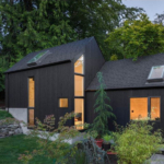 A compact, modern accessory dwelling unit (ADU) with a sleek design, featuring wood and metal siding, large windows, and a minimalist aesthetic, nestled within a lush, green residential setting.
